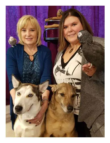 Two women and a dog are posing for the camera.