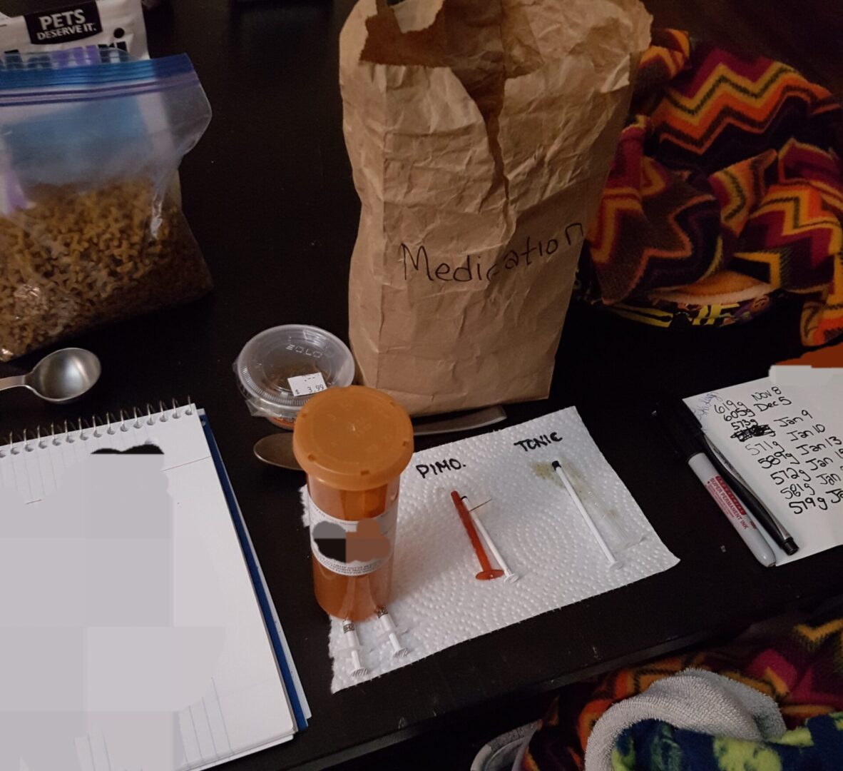 A table with papers, cups and a bag of cereal.