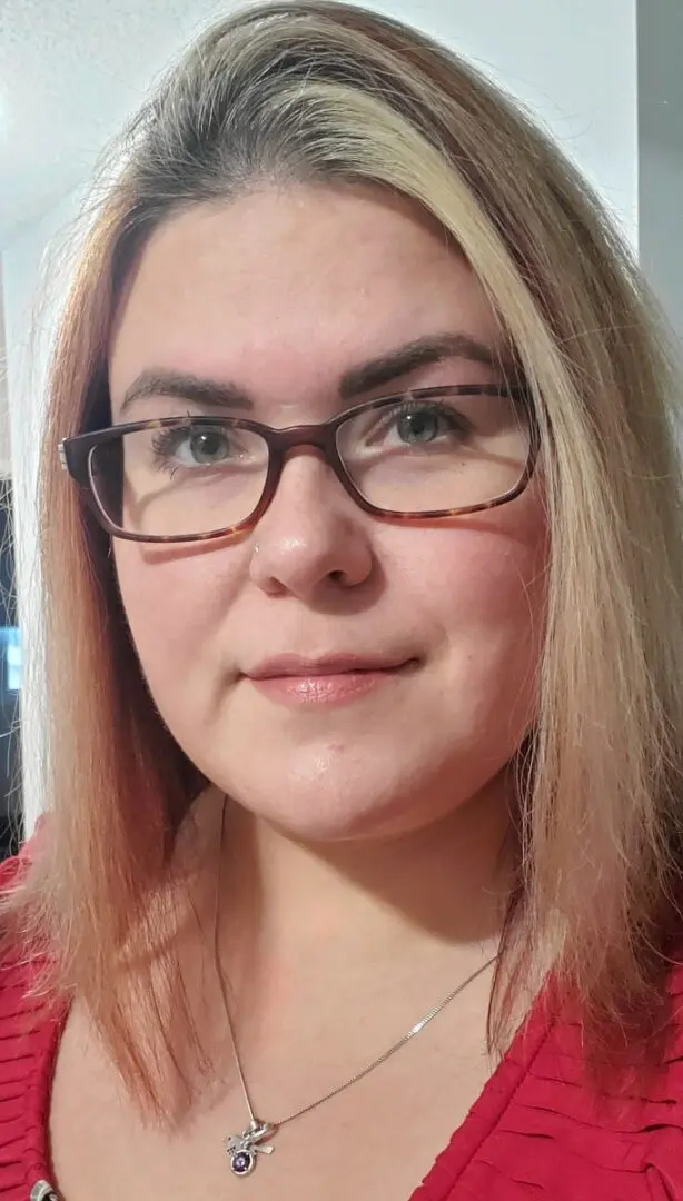 A woman with glasses and long hair wearing a red shirt.